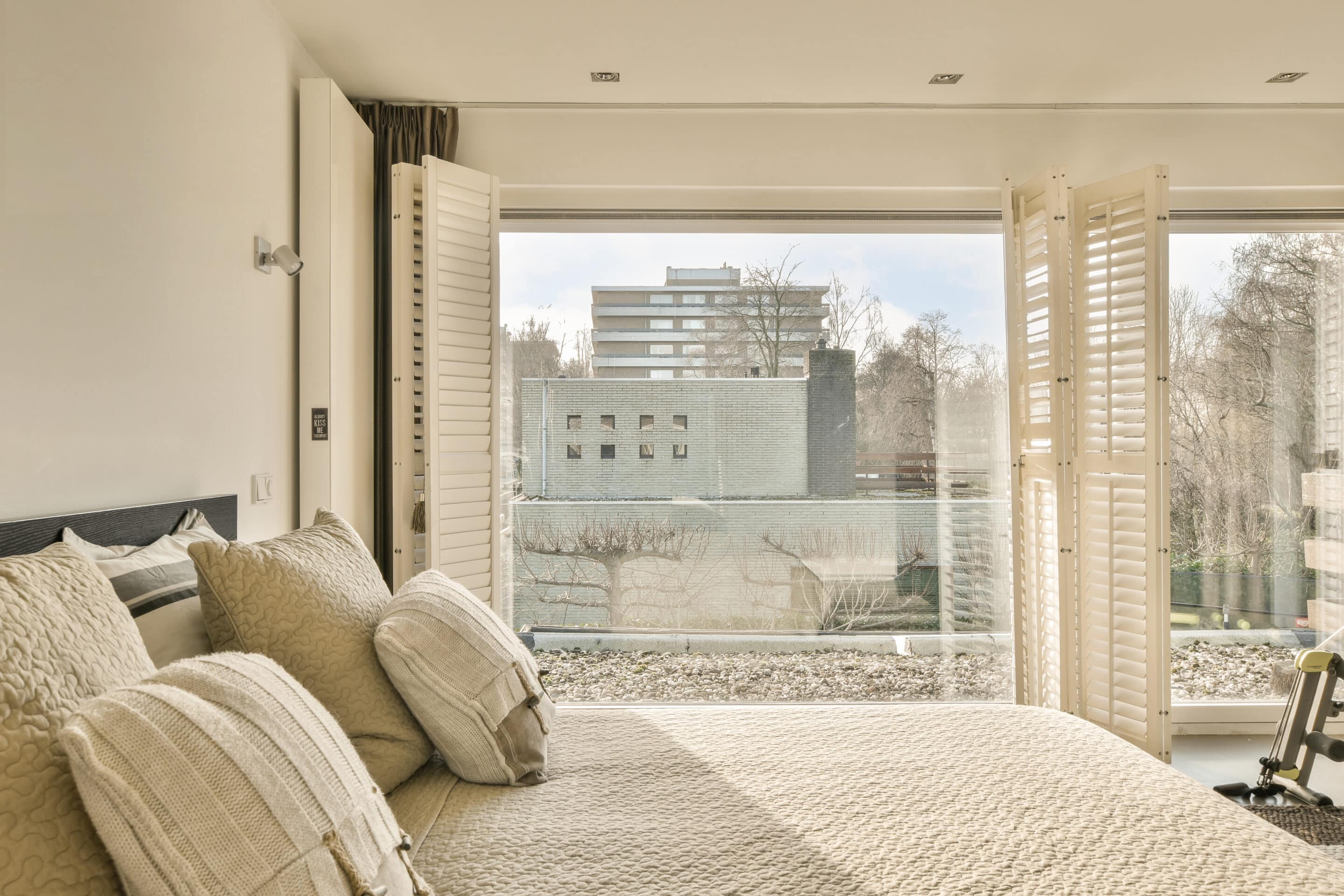 a bedroom with a large bed and a large window with bifold shutters