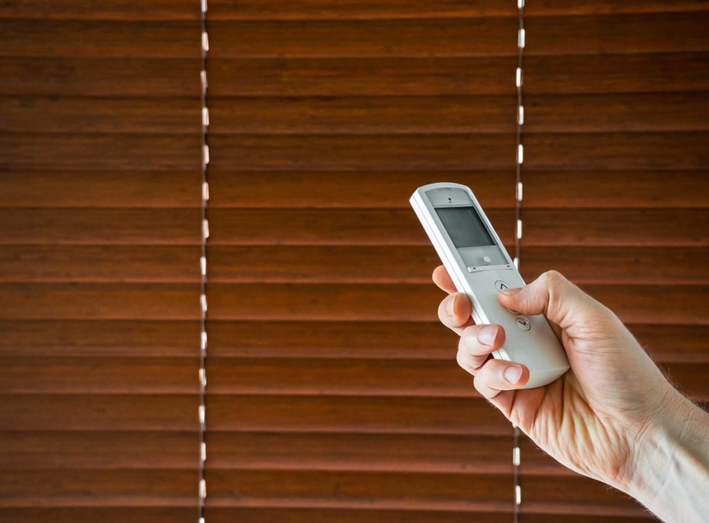 male hand holds a remote control to open the window blinds